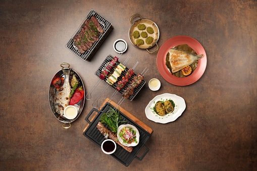 Restaurant food set with plates of food on a brown background, top view. Various food menu, view from above.