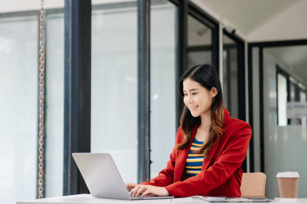 istock Young beautiful woman typing on tablet and laptop while sitting at the working white table 1794577440