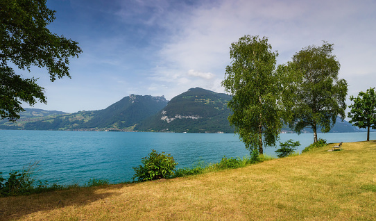 Beautiful idyllic view in switzerland on lake Thun in summer. Blue water with mountains panorama - panoramic view. Canton of Bern, Switzerland. Switzerland travel and landmarks.