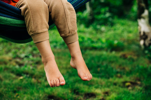 istock Closeup view on boy legs who sit hammock in outdoor 1794597377