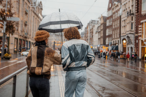 amsterdam day out in the rainy city for a diverse tourist couple - herfst-nederland stockfoto's en -beelden