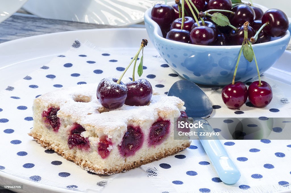 Cherry pie's bars with blue cup A slice of cherry pie on a linen napkin with polka dots. A cake decorated with fresh cherries. Next to a glass of juice. From the series "Homemade Cherry Pie" Baked Stock Photo