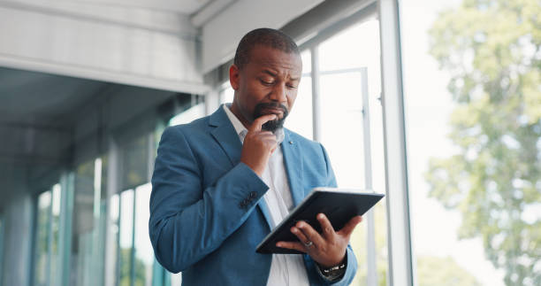 Thinking business black man with tablet for corporate review, strategy and idea for finance, budget and stock market in office building. Focus, data analytics and executive businessman on digital app hombre de negocios, tableta y pensando en la decisión del mercado de valores, la planificación de inversiones y la investigación financiera o de riesgo en la oficina. persona, comerciante o inversor africano en tecnología digital en duda para operar