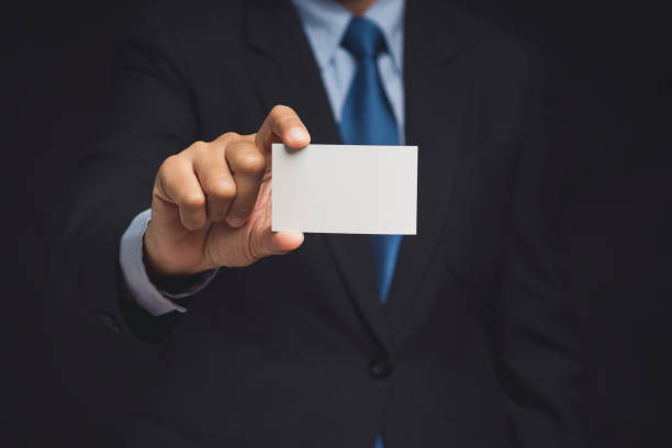 istock Businessman showing a blank white name card mockup while standing on a black background 1794630335