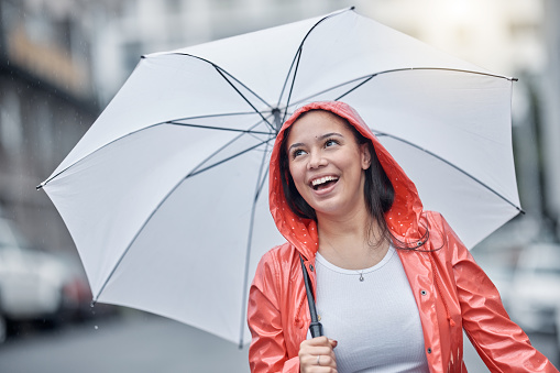 Outdoor, umbrella and black woman with smile, city and freedom on break, joyful and cheerful. Jamaican, female and lady with cover from rain, town and urban with happiness, comfortable and travel