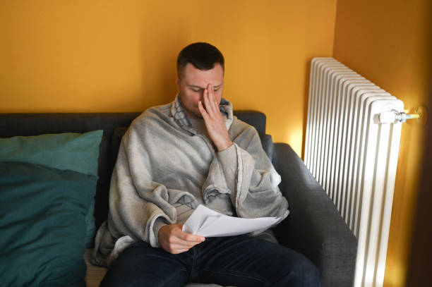 istock Unpleased man wrapped in blanket sitting on sofa 1794640856