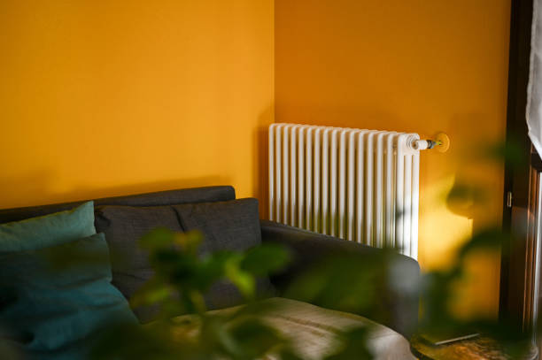 Person heating their hands at home over a domestic portable radiator in winter, energy crisis