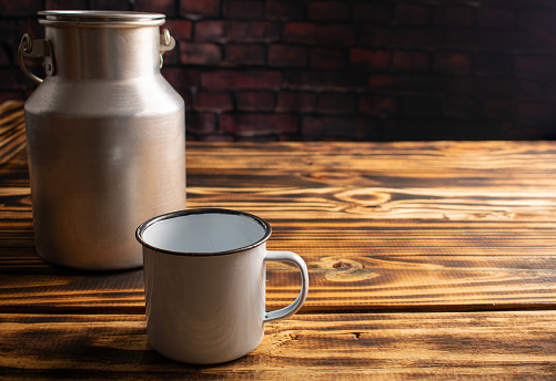 Rustic table, mug and antique milk can on rustic wood, selective focus.