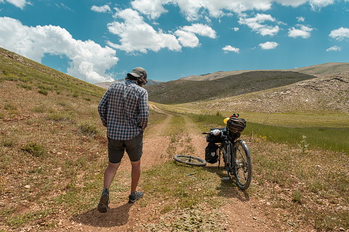 Repairing the tire of a 30-year-old model bicycle. Clear low cloud weather, mountainous region, extreme terrain, mountain ranges. Active lifestyle with high ability to live. Bikepacking style bicycle, tire repair. Overcoming difficulties. Where there are no people.