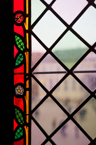 Close up of a beautiful colorful medieval stained glass window. Flower motifs. The bustle of the city in the background.