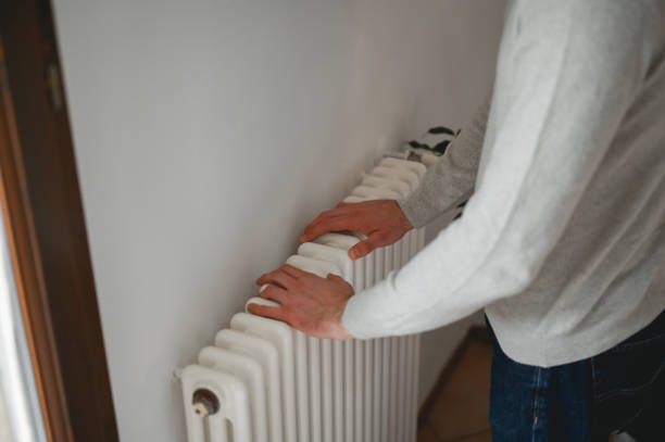 istock Unrecognizable man warming his hands on the radiator. 1794669461