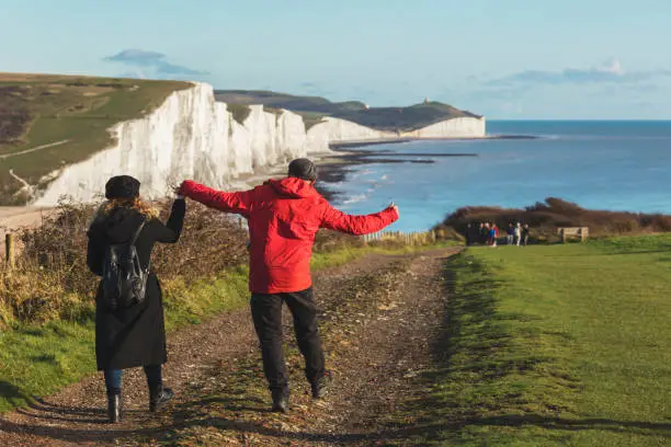 Newlyweds walk to the coastguard cottages set against the Seven Sisters, East Sussex, UK