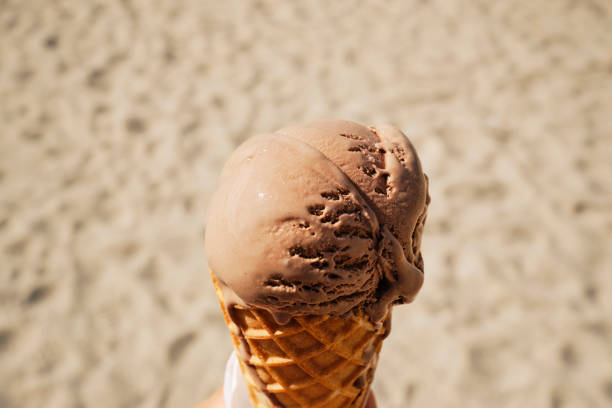 istock POV down onto a Chocolate Ice cream cone against a sandy beach on a sunny day. 1794709895