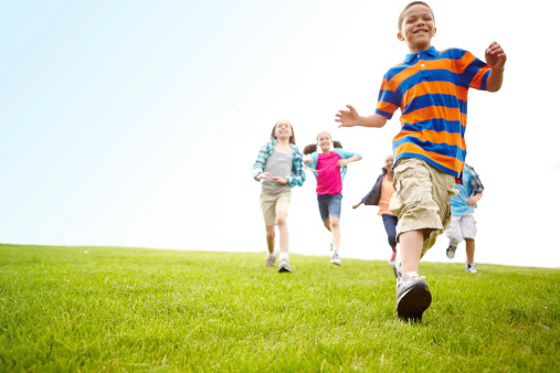 Group of energetic children running through a park together