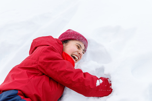 Girl in red snow coat smiling happily in the snow