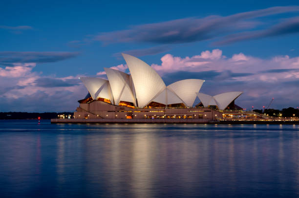 Sydney, Australia - July 23, 2023: Evening descends upon Sydney, and the iconic form of the city's Opera House can be seen across the waters of Circular Quay. Long exposure photo.