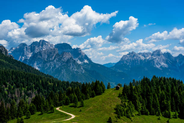 Dolomite mountains and Alps peaks with green meadows and rock spiers among woods and alpine pastures at an alpine hut in Gossaldo Belluno in the Belluno Dolomites Vicenza Veneto Italy