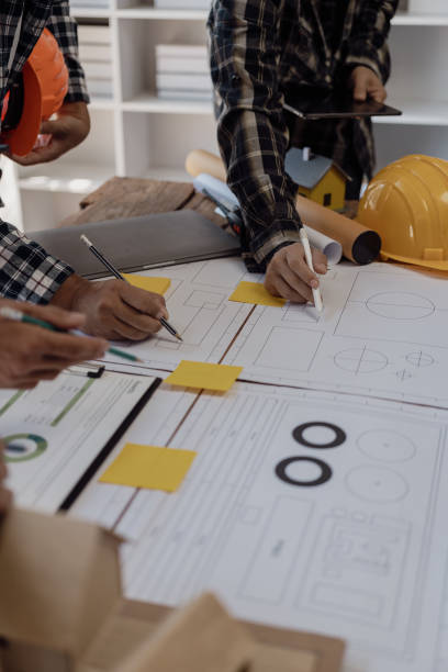 istock Professional architect, designer, team of colleagues discussing project. Building plan design and presentation Construction engineer and worker looking at building model and blueprint plan. 1794751557