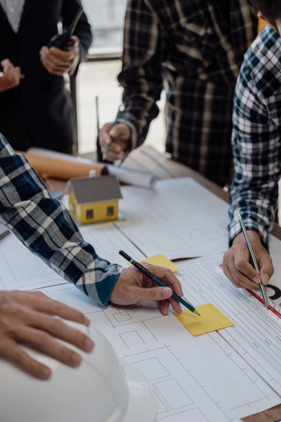 istock Professional architect, designer, team of colleagues discussing project. Building plan design and presentation Construction engineer and worker looking at building model and blueprint plan. 1794751562