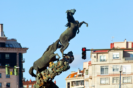 Spain square in downtown Vigo, Pontevedra province, Galicia, Spain. Horses sculpture set on traffic circle, Gran Vía avenue , clear sky background.