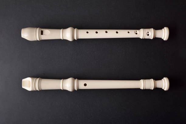 Top and bottom view of white plastic recorder on black textured table. Top view.