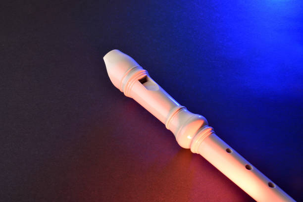 Conceptual concert background for recorder with detail of the instrument on black table illuminated with red and blue lights. Elevated view.