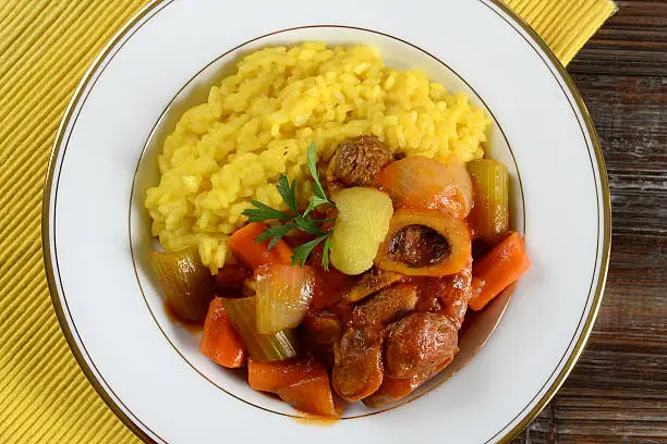 Osso Buco, the classic Italian dish of braised lamb shank with carrots, celery and tomatoes, served with risotto milanese.