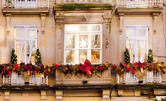 Balconies with  Christmas decorations.  flower pots, red Poinsettias, green leaves, wreaths. Stone house facade close-up, Vigo , Pontevedra province, Galicia, Spain.