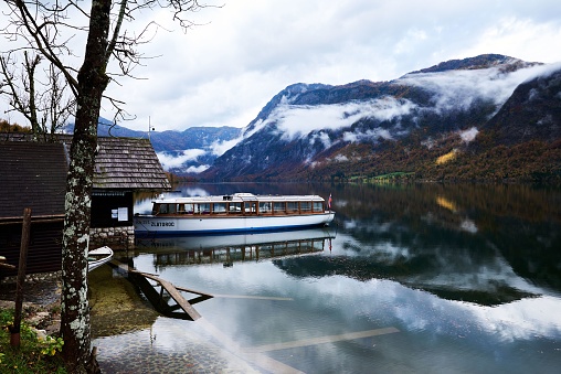 Bohinj, Slovenia – October 28, 2023: An idyllic scene of a boat docked at a wooden pier on the edge of a tranquil lake