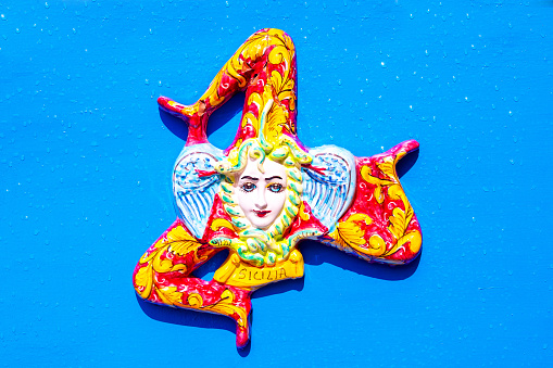 A typical ceramic trinacria, a traditional souvenir from Sicily, on a blue background. Trinakria or Trinakrien the symbol and name of the island since Homer.