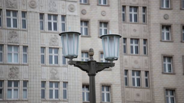 A vintage-style street lamp with two bright white bulbs illuminating the path in front of a grand, towering structure