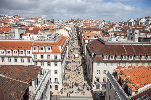 Embrace the dynamic energy of Lisbon's city center from a captivating rooftop perspective. This striking image captures the bustling streets below, adorned with people immersed in the lively rhythm of urban life. The city's heartbeat unfolds against the backdrop of architectural charm, offering a vibrant snapshot of the lively pulse of Lisbon