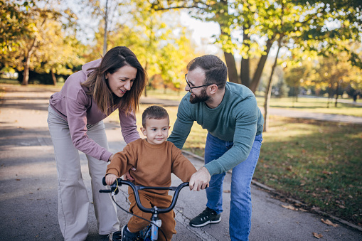 Father, mother and son in park riding a bicycle in the park