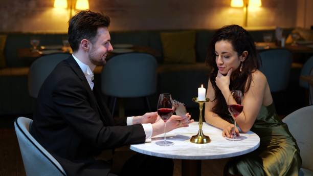 istock Happy man showing smartphone for his girlfriend while having romantic date in the restaurant. Lifestyle, love, relationships concept. Slow motion 1794839179