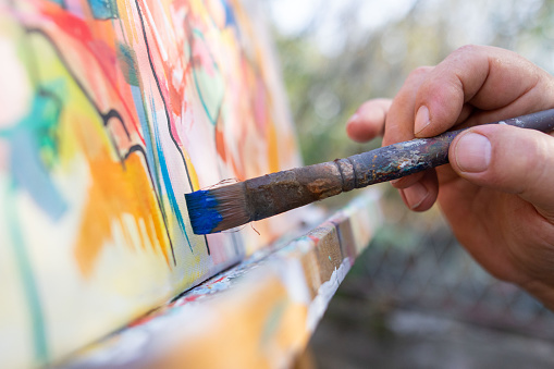 Fine art painter painting outdoor, Close up of artist holding brush