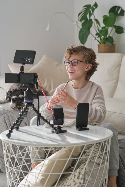 istock Boy laughing while recording video for blog at home 1794872362