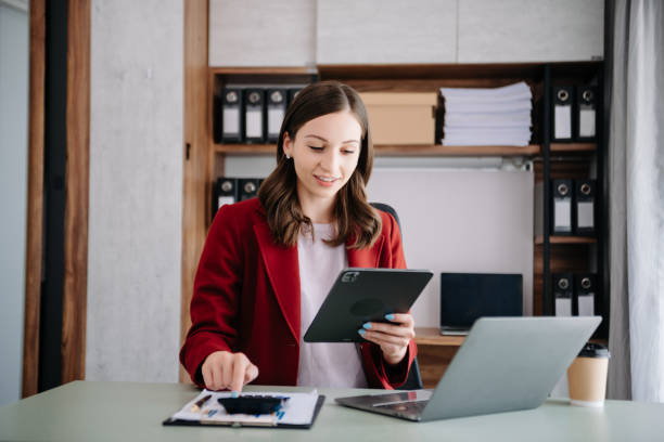 istock Confident woman with a smile standing holding notepad and tablet at the modern office. 1794873686