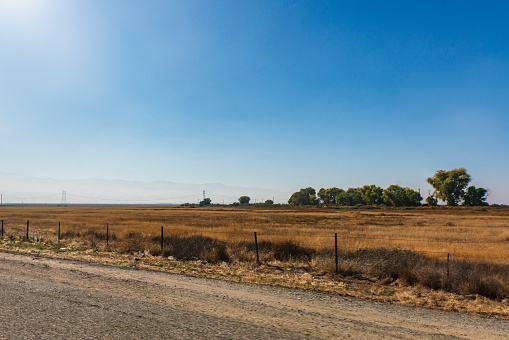 Agricultural Fields along side California Route 99 with Mountains in the Background and a Clear Blue Sky