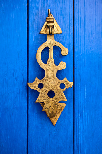 Close up of decorative metal door knocker on a blue door in Chefchaouen, Morocco, Africa.
