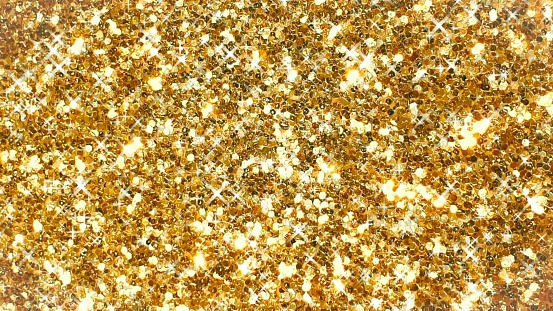 An abstract image of a golden glittered background, with sparkles and light shining through