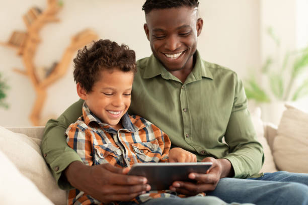 istock Happy Black Man And His Son Using Digital Tablet Indoors 1794916306