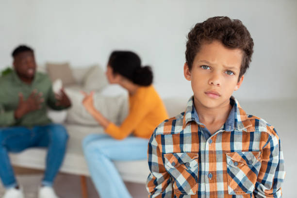 istock Unhappy boy looking at camera while parents fighting on background 1794916905