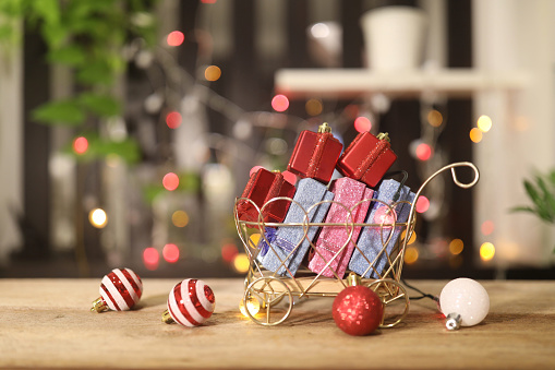 Gift box in a shopping cart with Christmas bokeh light bulb