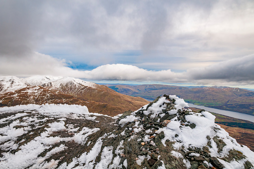 Panoramic view over the snowy mountains of the Highlands in Scotland during an overcast day in winter. Picture taken from Meall Corranaich munro.