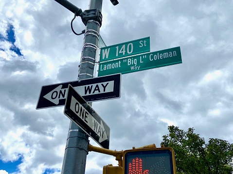 New York, NY USA - August 8, 2023 : Looking up at green street signs on the corner of W 140th Street co-named Lamont \