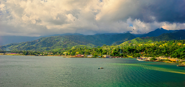 Looking from above at the fishing village of Alotau, Milne Bay PNG and its cloud covered mountainous background in early evening.