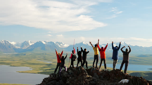 Group of hikers joy with success in travel standing on top of high mountain