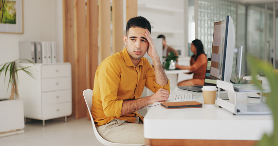 Stress, depression and business man at table in office for challenge, financial crisis or bankruptcy in startup. Frustrated, anxiety and sad professional thinking of bad news, tax debt and mistake