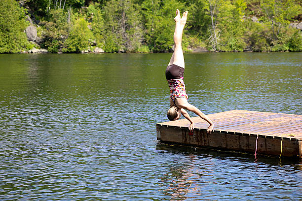Woman Diving Doing a Hand Spring A woman is diving off the dock doing a hand spring into the water. This is in a lake in Muskoka, Ontario, Canada. handspring stock pictures, royalty-free photos & images