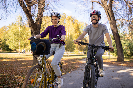 A mid adult Caucasian man and woman riding their bikes together in a public park